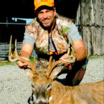 A man poses with his deer at Long Creek Outfitters