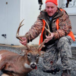 A hunter poses with his deer at Long Creek Outfitters